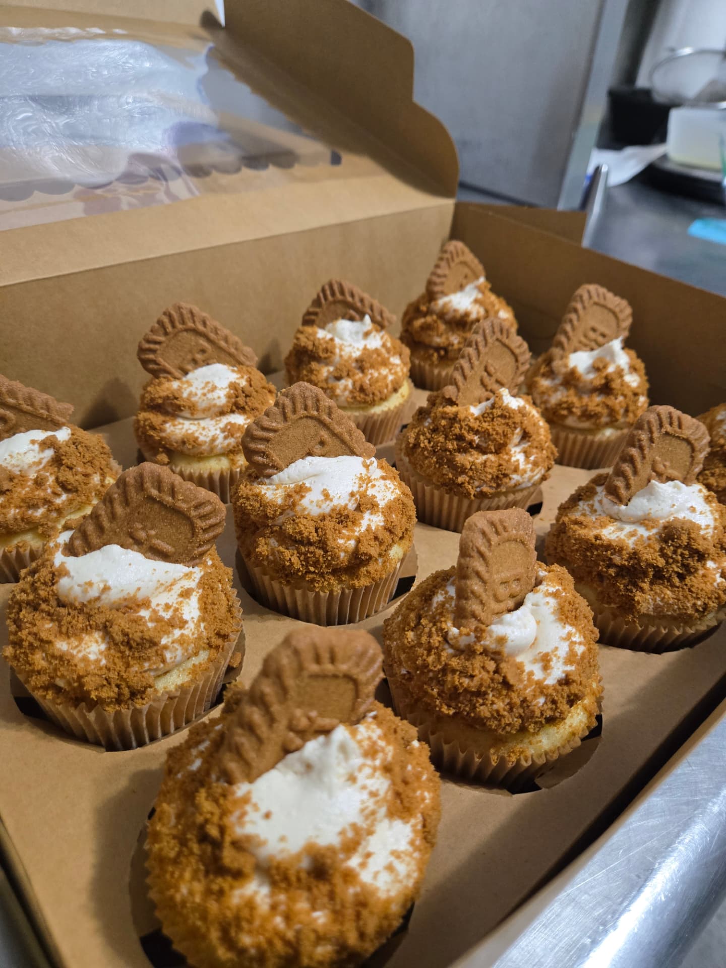 A bakery box filled with Biscoff cupcakes topped with cookie butter frosting, crumb, and a speculoos cookie